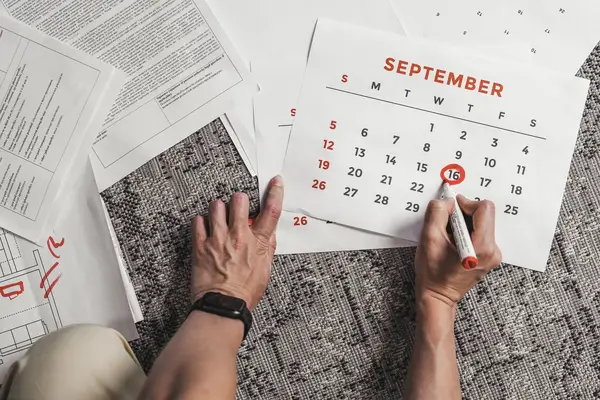 Hand markiert einen Termin im Kalender