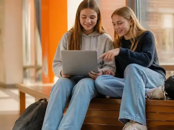 Zwei Sch&uuml;lerinnen sitzen im Schulflur und schreiben gemeinsam am ersten Lebenslauf
