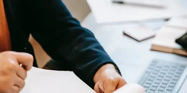 H&auml;nde schreiben neben einer Tastatur auf Papier