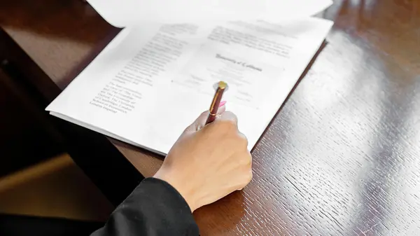 Hand f&uuml;llt mit einem Stift ein Dokument aus