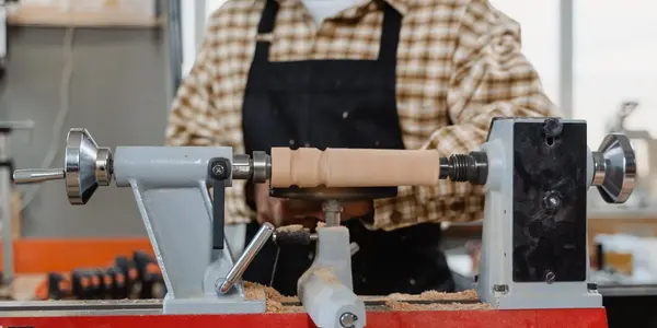 Handwerker arbeitet mit Sch&uuml;rze an einer Drechselbank
