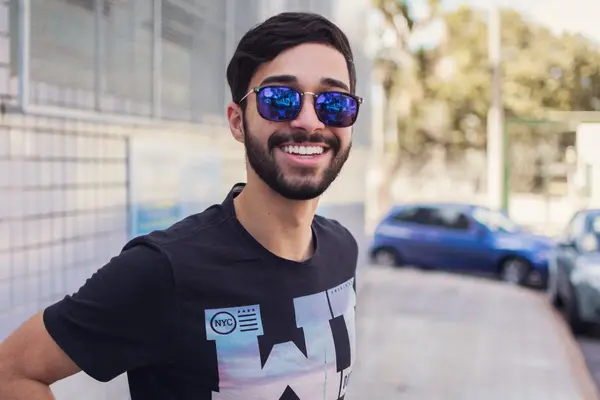 Junger Mann mit Sonnenbrille lacht in die Kamera