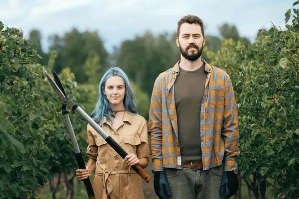 Zwei junge Menschen mit Gartenwerkzeug in der Natur